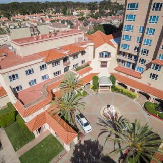 Aerial view of a hotel featuring distinct architecture, surrounded by palm trees and rooftops.