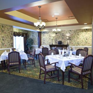 A well-decorated dining area with neatly arranged tables and chairs under elegant chandeliers.