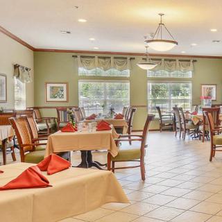 A well-lit dining area with neatly arranged tables and chairs, set with tablecloths and napkins.
