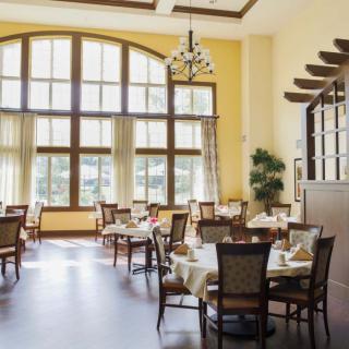 A well-lit dining area with large windows and elegantly set tables.