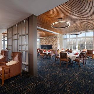 A modern dining area with wooden ceilings and large windows, featuring neatly arranged tables and comfortable seating.