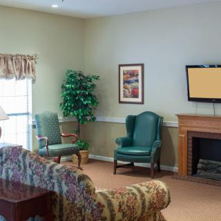 A cozy living room with armchairs, a patterned sofa, and a fireplace.