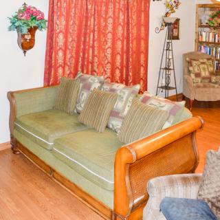 A cozy living room with a wooden sofa, adorned with patterned cushions, and red curtains adding warmth to the decor.