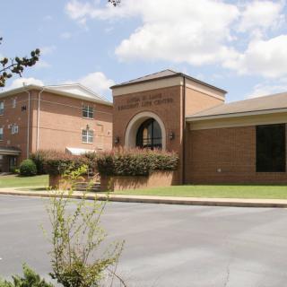 A brick school building with a prominent entrance under a partly cloudy sky.