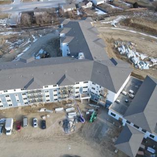 An aerial view of a large building under construction, surrounded by vehicles and construction materials.