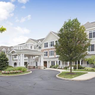 A large and elegant residential building with well-maintained landscaping and a circular driveway.