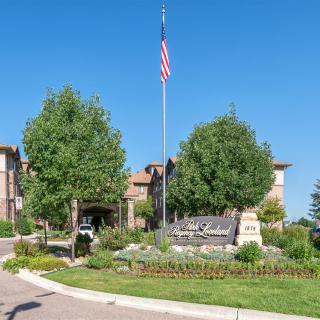 A landscaped entrance to a residential or commercial complex with a flagpole and sign.