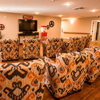 A cozy home theater room with patterned seating and a large television, complemented by a popcorn machine.