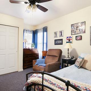 A cozy bedroom with a bed, armchair, and decorative items on the walls.