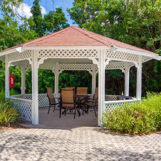 A charming gazebo with patio furniture set in a lush garden.