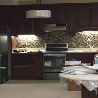 A modern kitchen with dark cabinetry, stainless steel appliances, and a stylish backsplash.