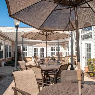 A cozy outdoor patio with tables and chairs under large umbrellas on a sunny day.