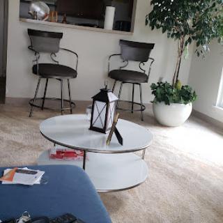 A modern living room setup featuring a stylish coffee table, two bar stools, and an indoor plant.