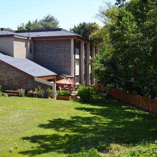 A residential building with a well-maintained lawn and surrounding trees on a sunny day.
