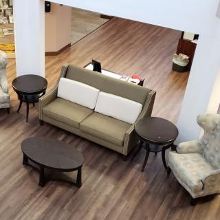 A cozy living room setup with a sofa, two round tables, and an armchair on a wooden floor.