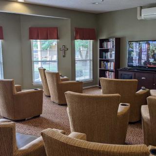 A cozy lounge area with comfortable chairs facing a television and bookshelf.