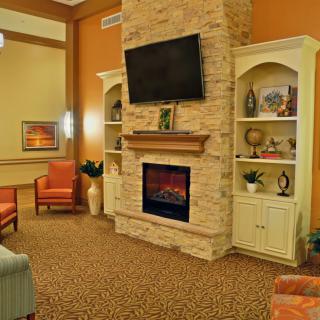 A cozy living room with a stone fireplace, TV, and comfortable seating.