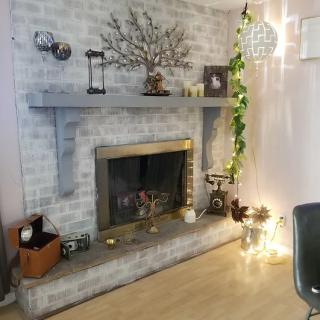 A cozy living room with a decorated fireplace featuring plants and candles.