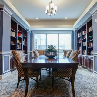 A stylish dining room with a library setting featuring bookshelves and elegant furniture.
