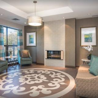 A modern living room featuring comfortable seating, a fireplace, and large windows allowing natural light.
