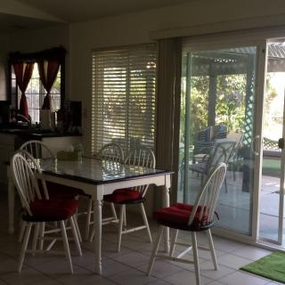 A dining area with a table and chairs, featuring natural light from a large sliding glass door.