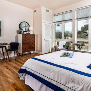 A modern bedroom with large windows allowing natural light to flood the space, featuring elegant furniture and a cozy atmosphere.