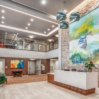 A modern lobby with sleek interior design, featuring a large piece of colorful artwork and contemporary lighting fixtures.