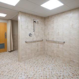 An accessible shower room with handrails and a tiled floor.