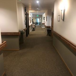 A well-lit, carpeted hallway with handrails and wall-mounted lights.