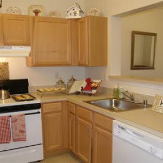 A cozy kitchen with wooden cabinets, a stove, dishwasher, and sink.