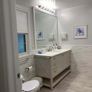 A modern bathroom with a large vanity, mirror, and elegant lighting.
