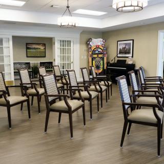 An empty conference room with neatly arranged chairs and a piano in the corner.