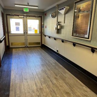 A well-lit hallway featuring two doors at the end and visible handrails along the walls.