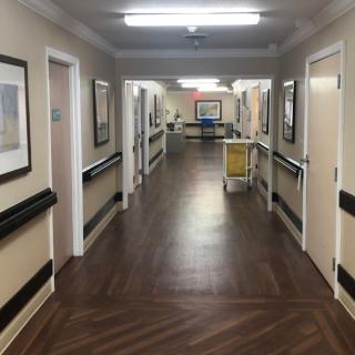 A well-lit hospital corridor lined with doors and handrails.