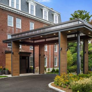 A modern hotel entrance with a brick exterior and landscaped surroundings.