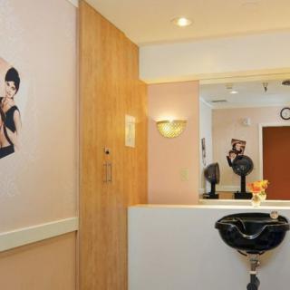 A modern hair salon interior featuring a styling chair, mirror, and wall art.