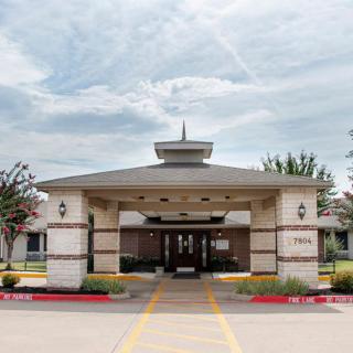 A covered entrance to a building with a cloudy sky overhead.