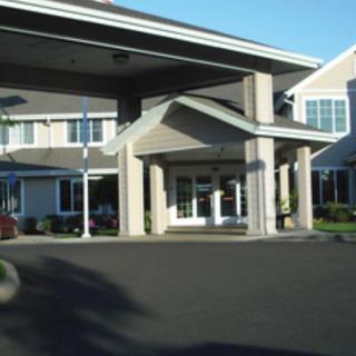 Entrance of a building with a covered driveway and columns.