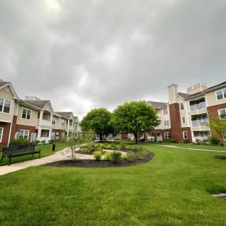 A well-maintained apartment complex with lush greenery under a cloudy sky.