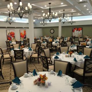 An elegantly arranged dining room ready for guests, featuring decorated tables and stylish chandeliers.