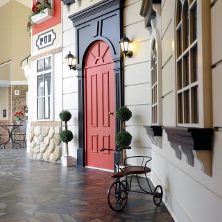A stylish interior space featuring a red door with decorative plants and vintage bicycle accents.