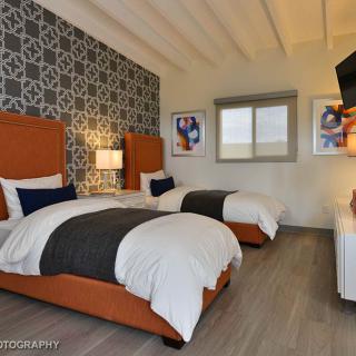 A modern bedroom with twin beds and stylish decor, featuring patterned wallpaper and contemporary furnishings.