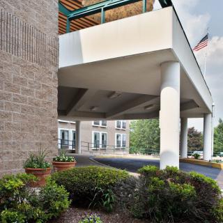 A modern building entrance with landscaping and prominent columns.