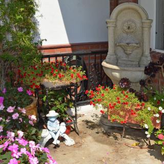 A charming garden corner with colorful flowers, a decorative fountain, and a garden ornament.