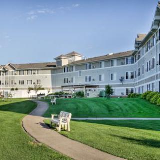 A large hotel building with a well-maintained lawn and a pathway leading to a bench.