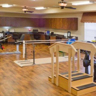 A rehabilitation room equipped with parallel bars and exercise equipment.