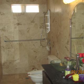 A modern bathroom with tiled walls, featuring a shower, toilet, and sink area.