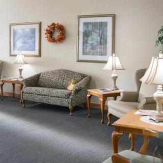 A waiting room with comfortable seating, lamps, and decorative artwork on the walls.