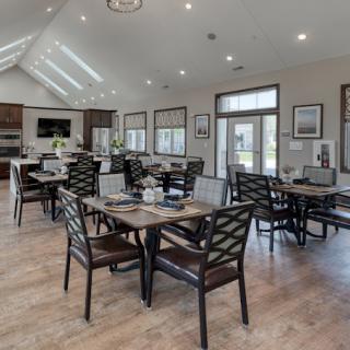 A spacious and modern dining area with several tables and chairs, featuring wooden flooring and stylish lighting fixtures.