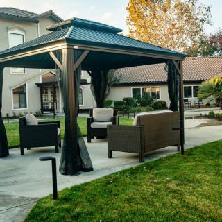 A backyard patio with a gazebo and outdoor furniture.